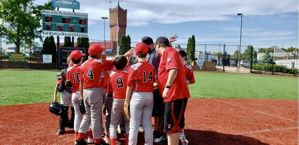Boys baseball team huddle water tower and scoreboard in background